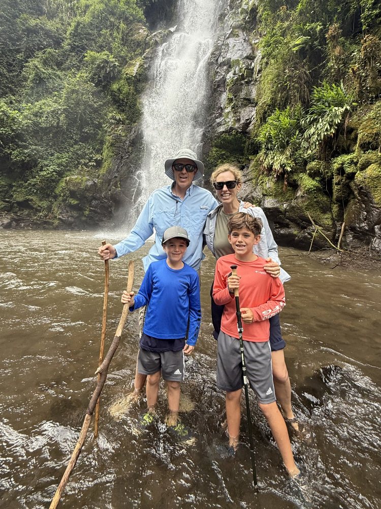 Ali, Andres, Tomás and Lucas standing in a river in front of a waterfall